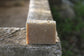 the healthy promise soap handcrafted all natural goats milk and honey on a stone wall back side on a stone wall
